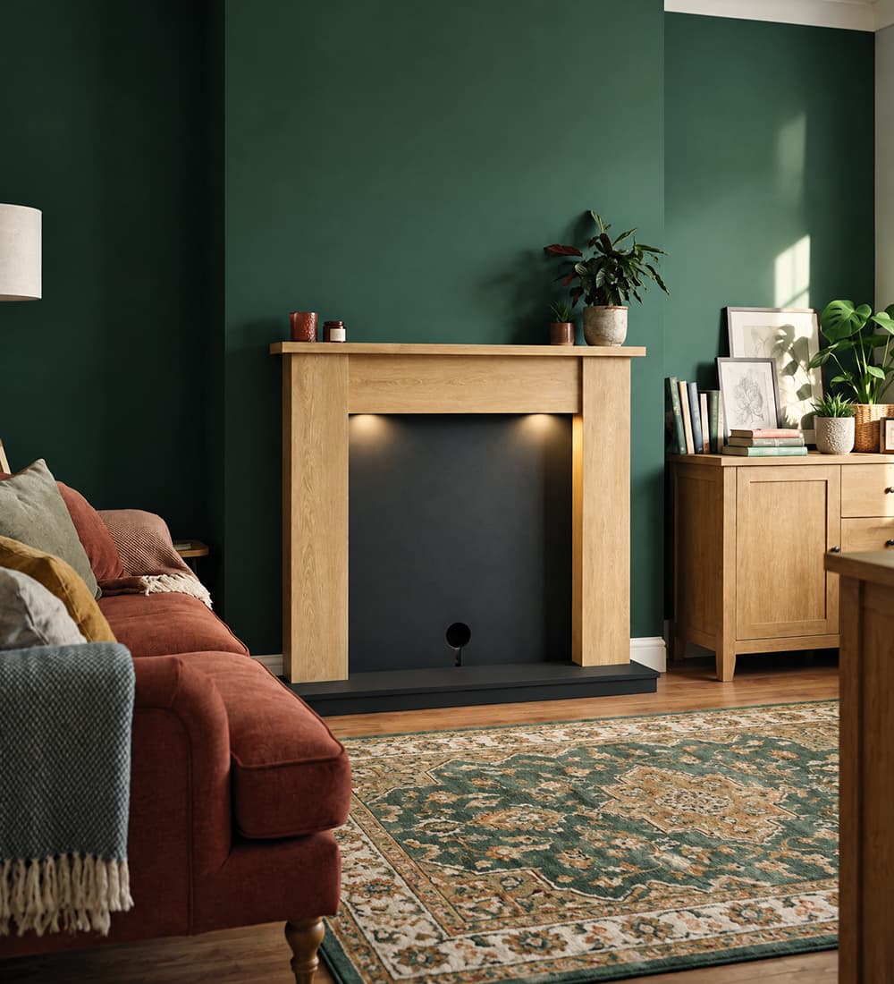 Flare Barrowden fireplace suite in natural oak effect with anthracite hearth and back panel, styled without a fire in a green living room.